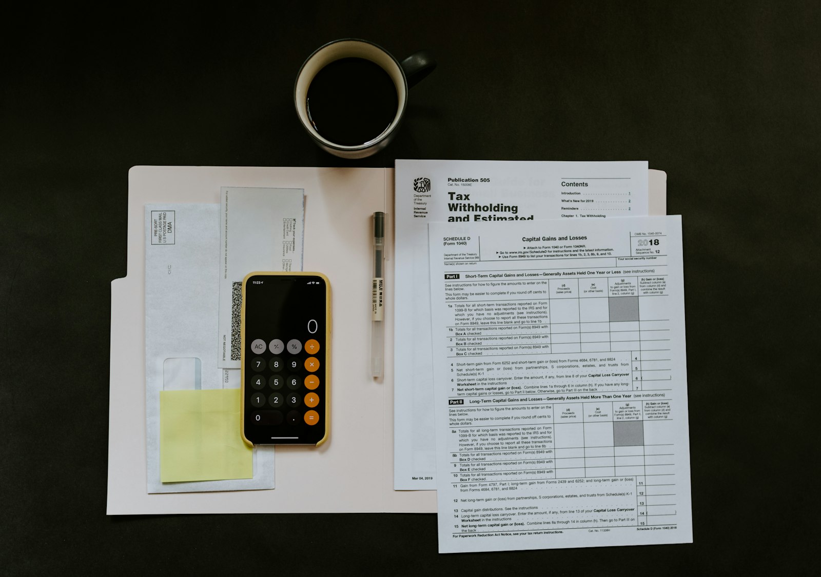 black Android smartphone near ballpoint pen, tax withholding certificate on top